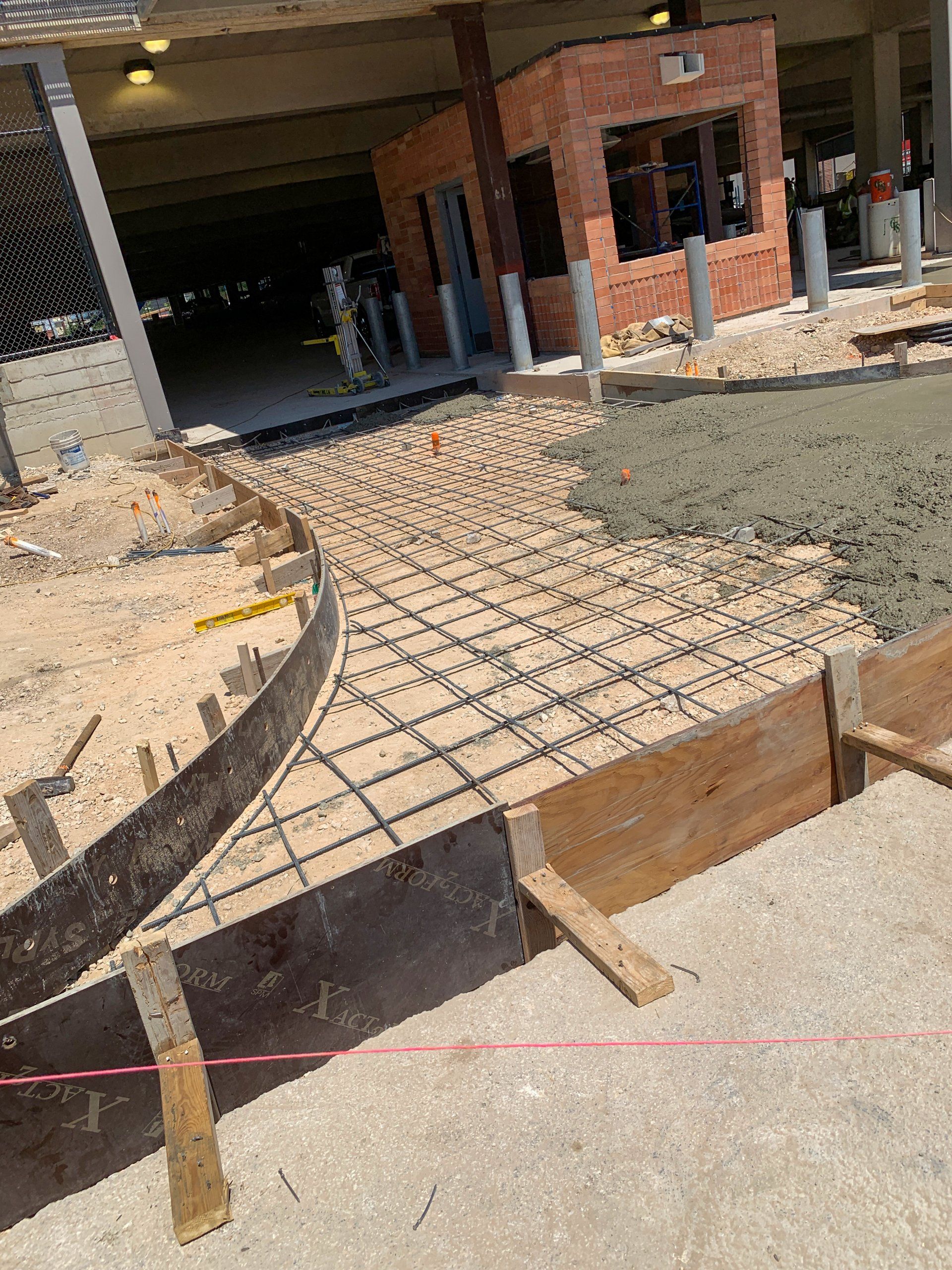A concrete walkway is being built in front of a parking garage.