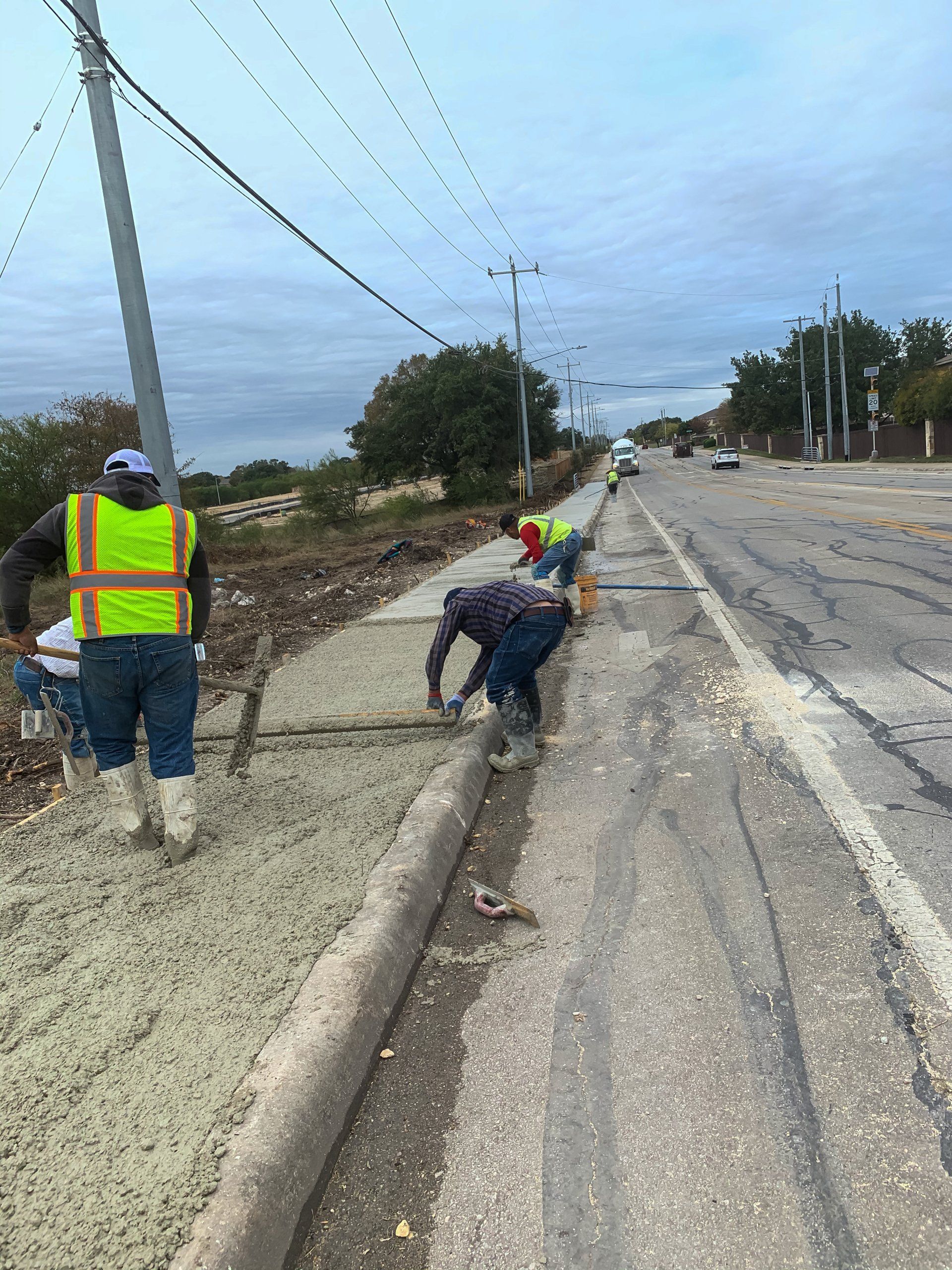 A group of construction workers are working on the side of a road.