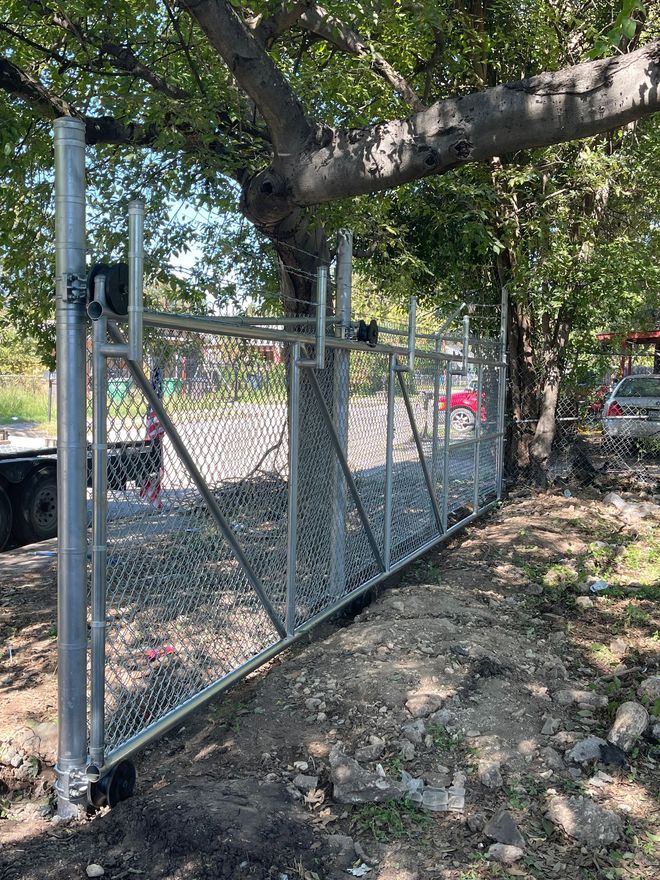 A chain link fence is being built next to a tree.