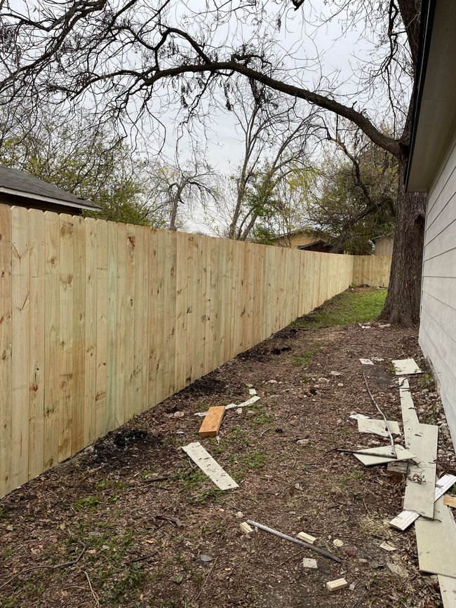 A wooden fence is being built in the backyard of a house.