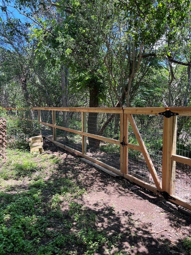 A wooden fence with a gate in the middle of a forest.