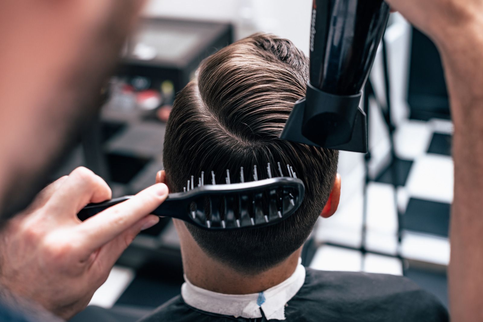 A man is getting his hair blow dried by a barber.