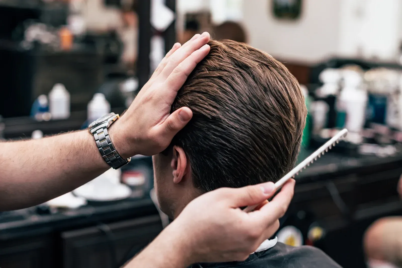 A man is getting his hair cut by a barber in a barber shop.