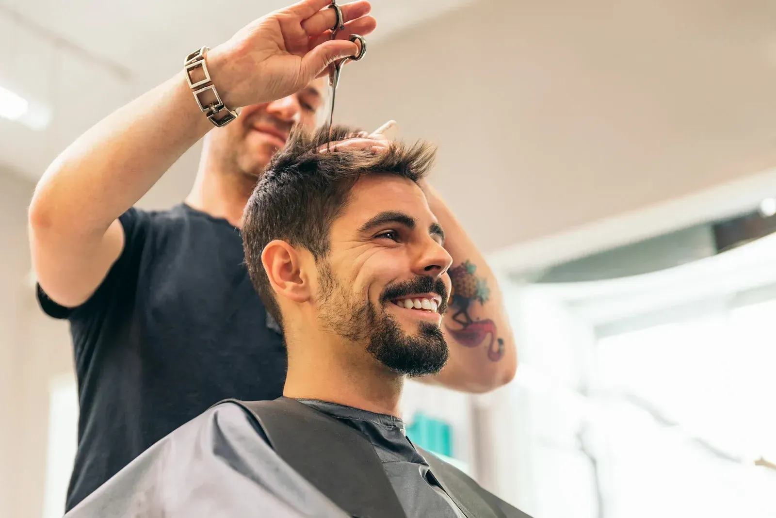 A man is getting his hair cut by a barber in a salon.