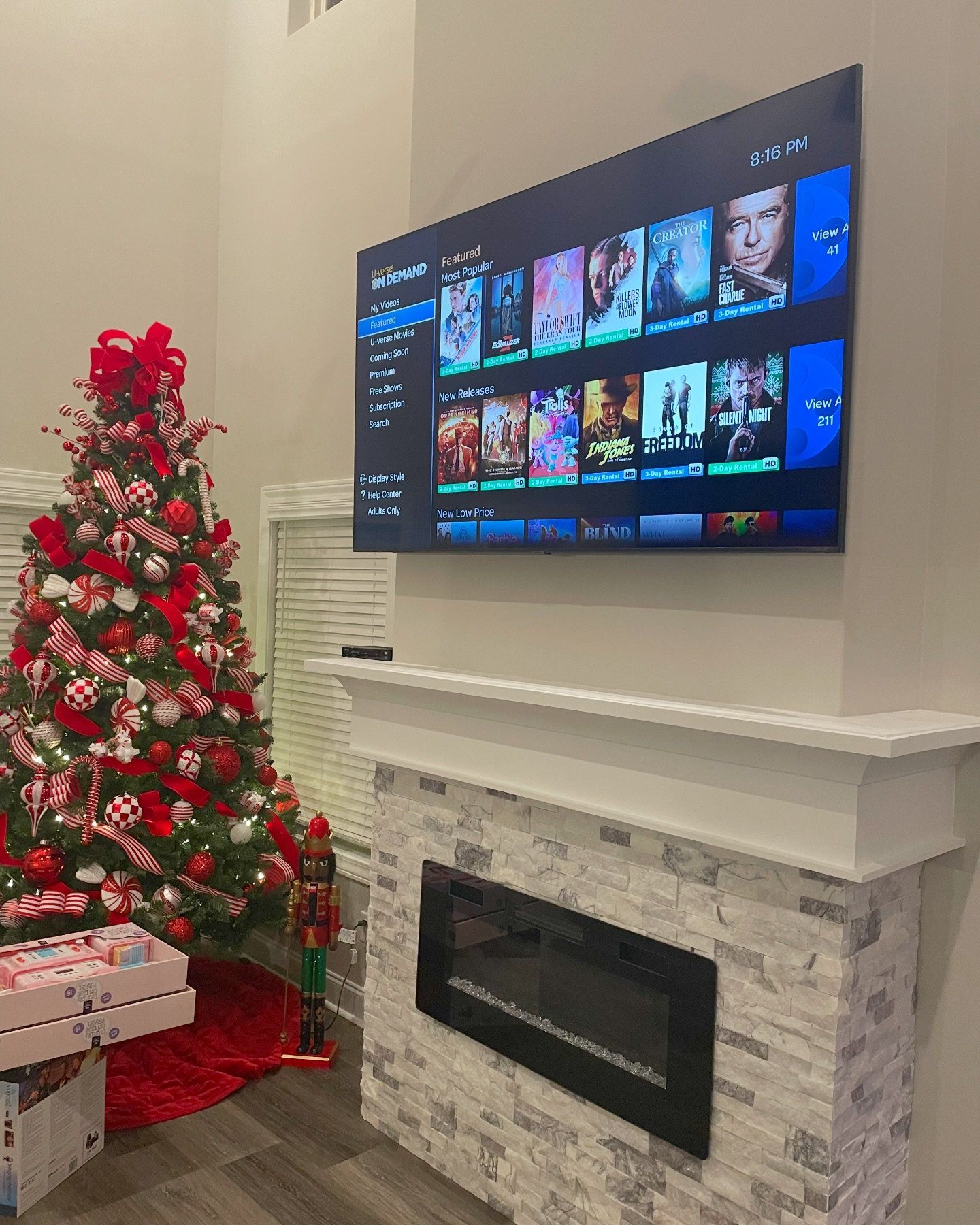 Christmas tree, fireplace, and TV displaying streaming content. White and red decor. Living room setting.