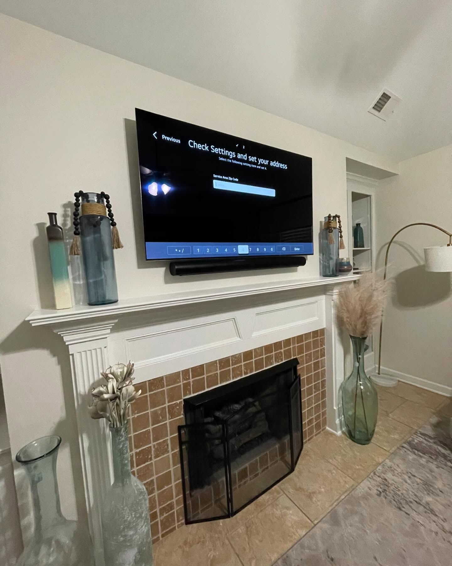 A TV mounted above a fireplace, flanked by decorative vases.