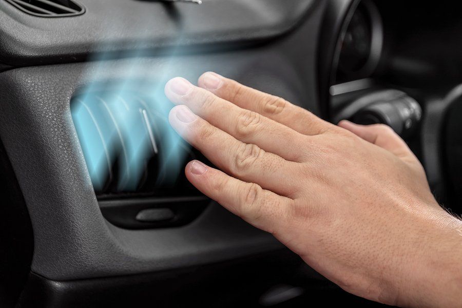 A person is touching the air vent in a car.