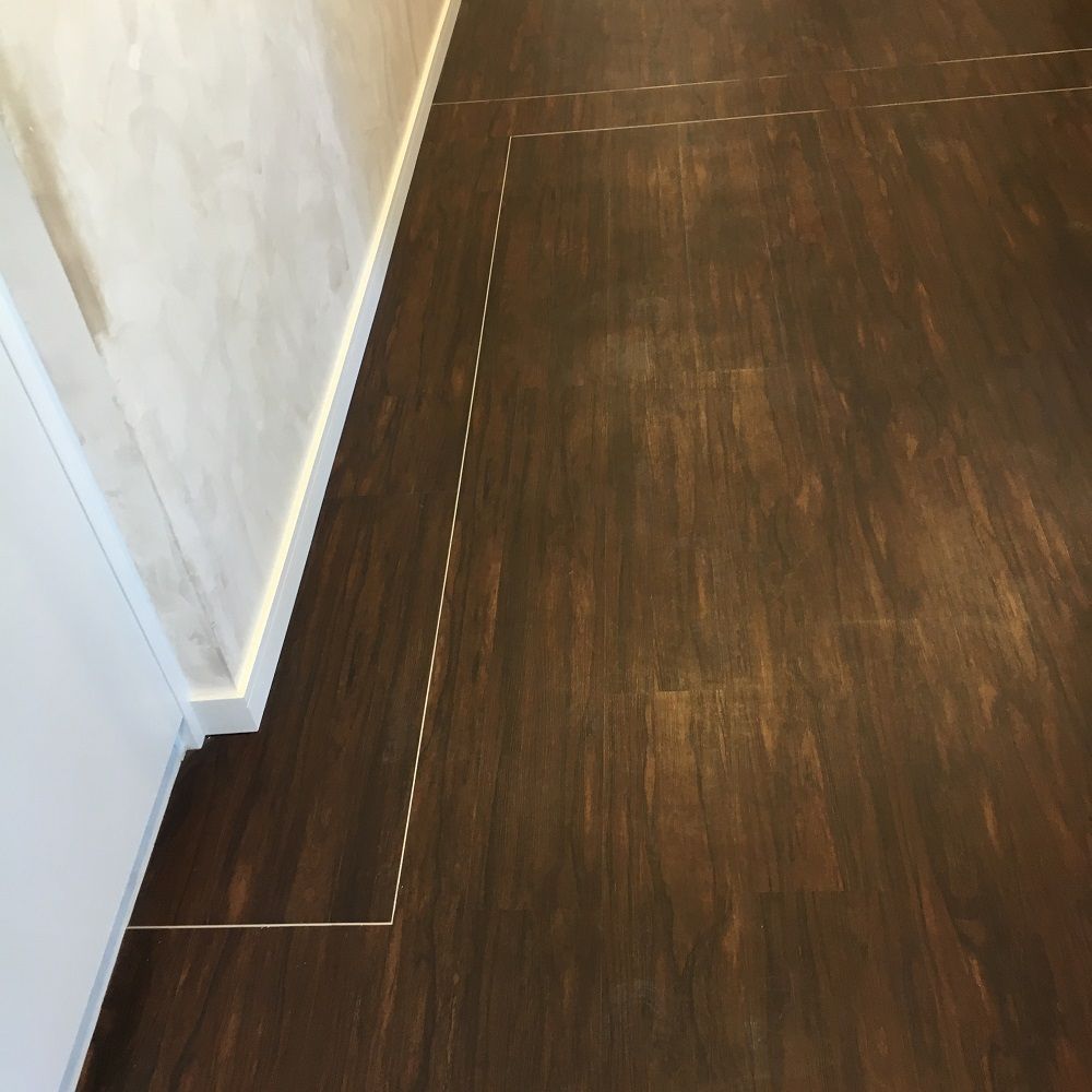 Un couloir avec un plancher en bois et un mur blanc.