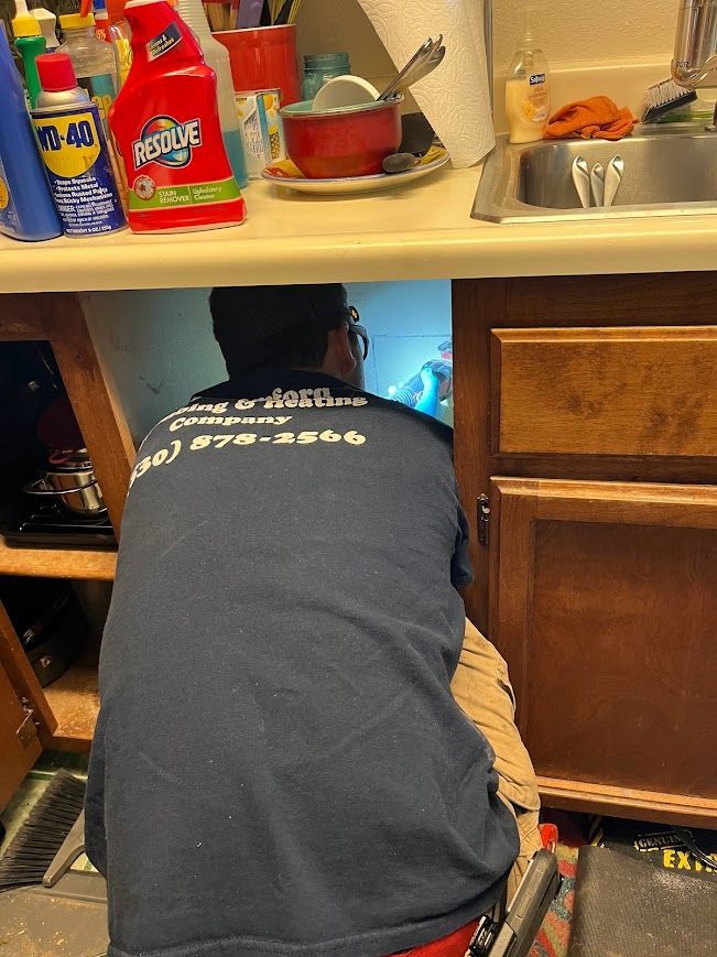 A man is kneeling under a sink in a kitchen.