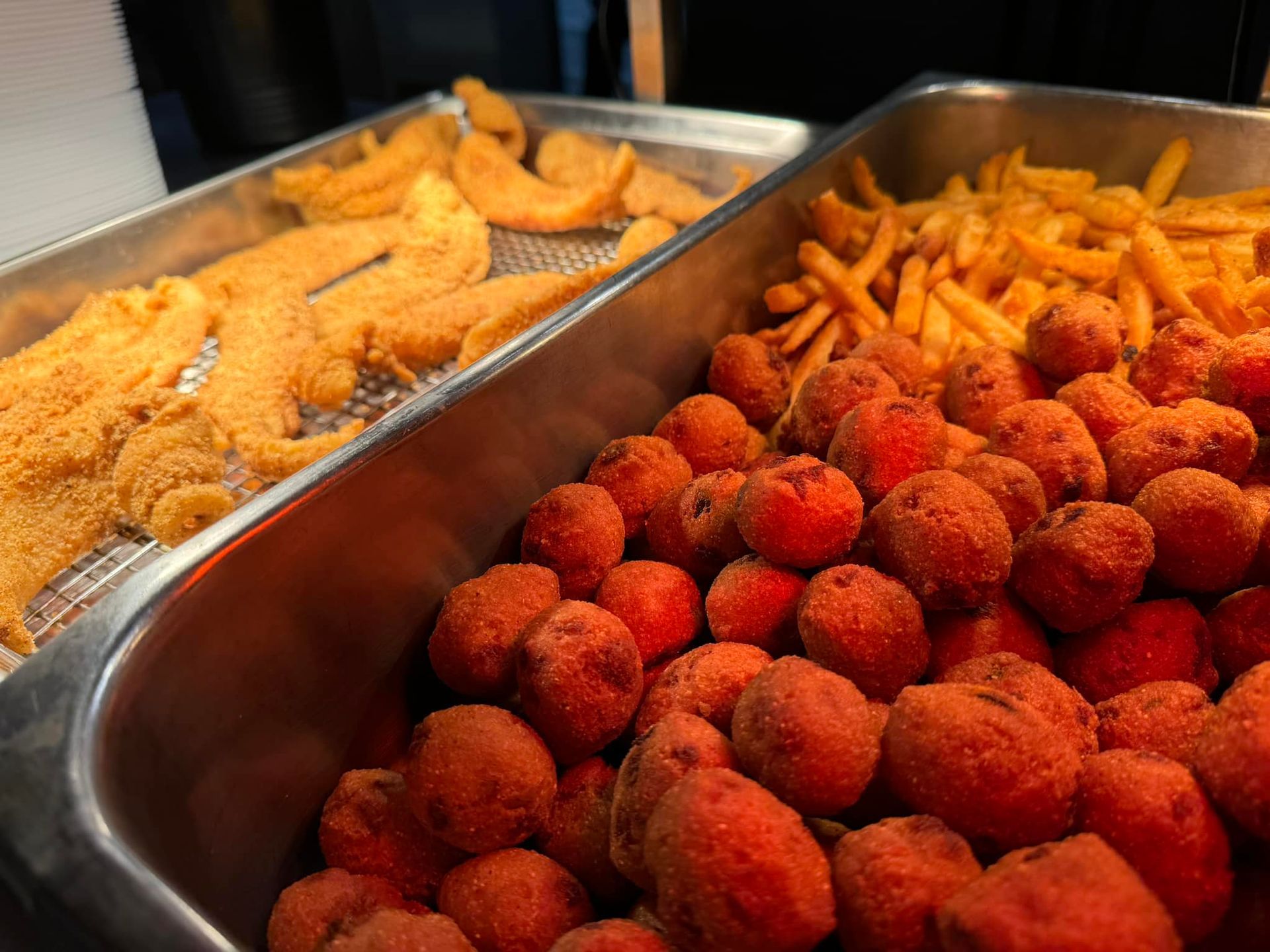 A tray of fried food including fish and french fries.