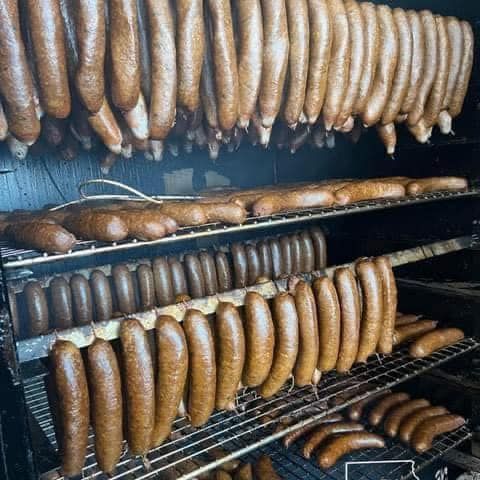 A bunch of sausages hanging on a rack in a smokehouse.