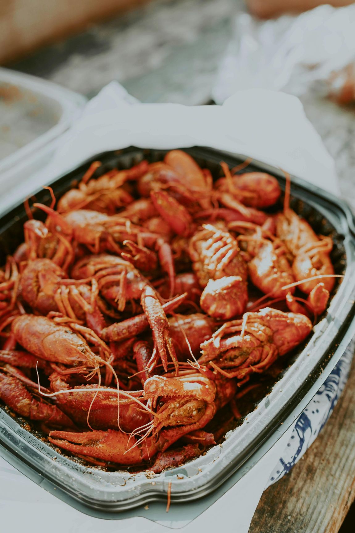 A tray of cooked crawfish is sitting on a wooden table.