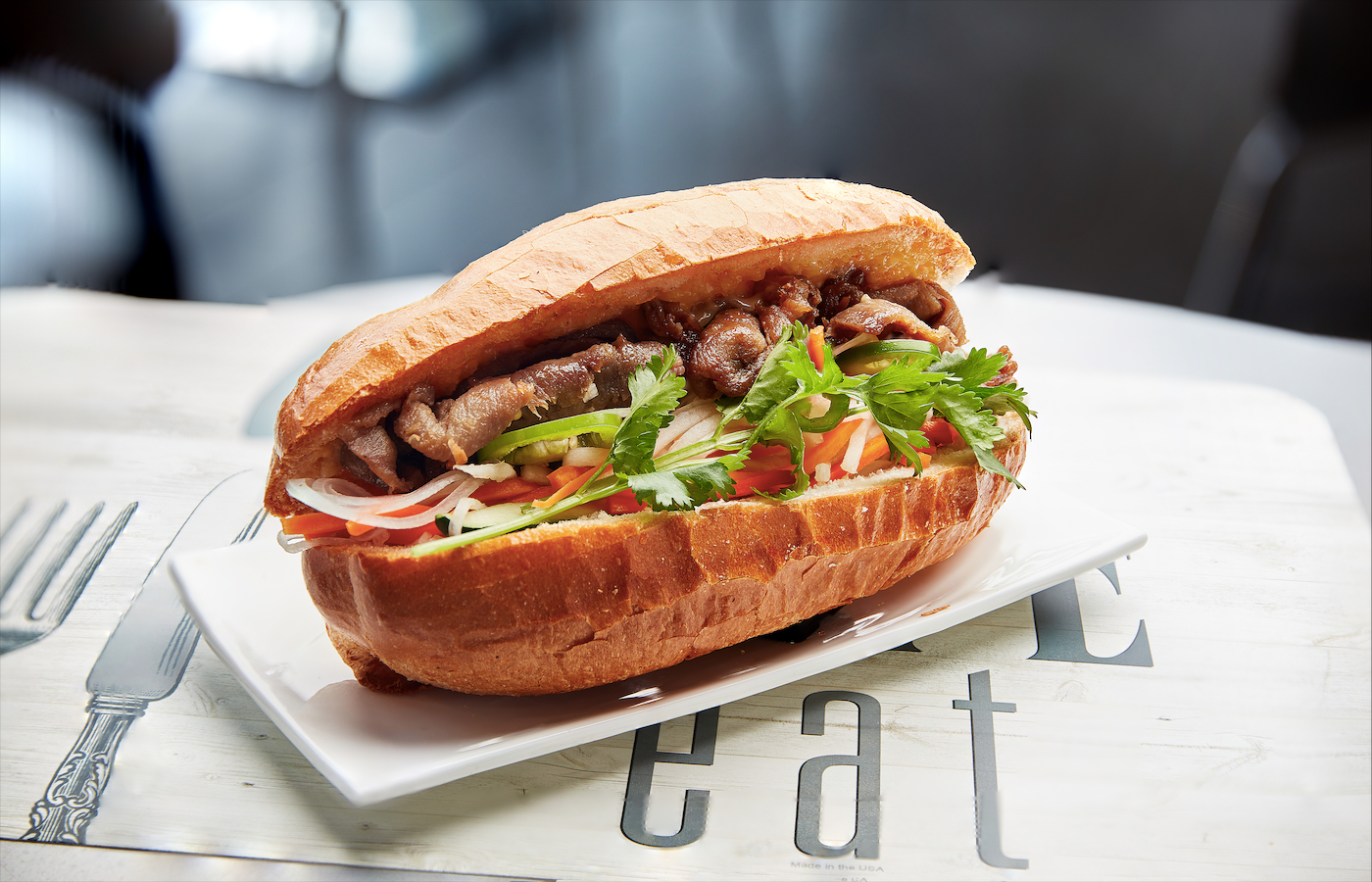 A sandwich is sitting on a white plate on a table.