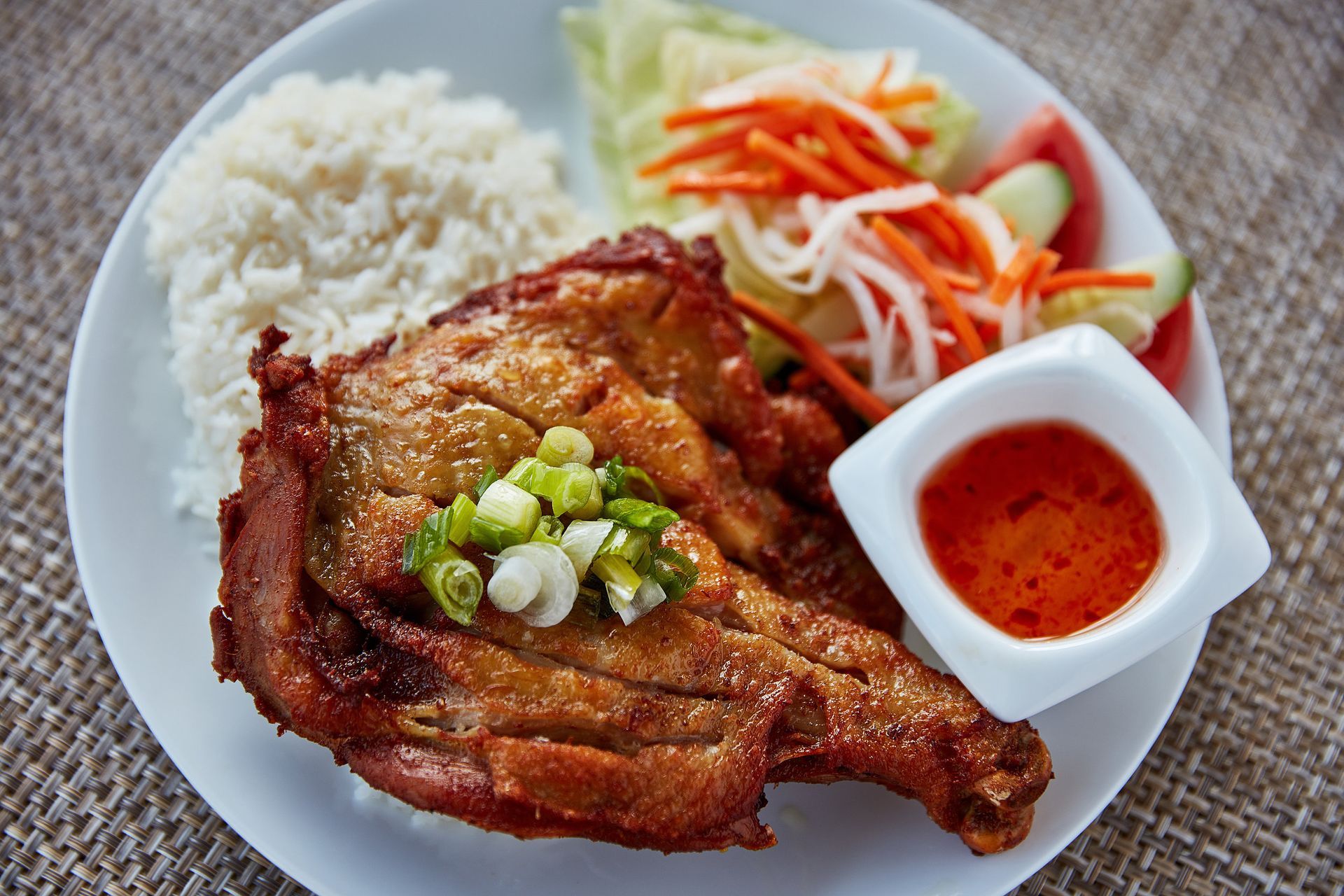 A white plate topped with meat rice and vegetables