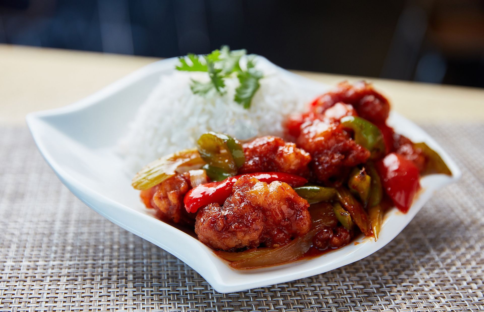 A white plate topped with meat and rice on a table.