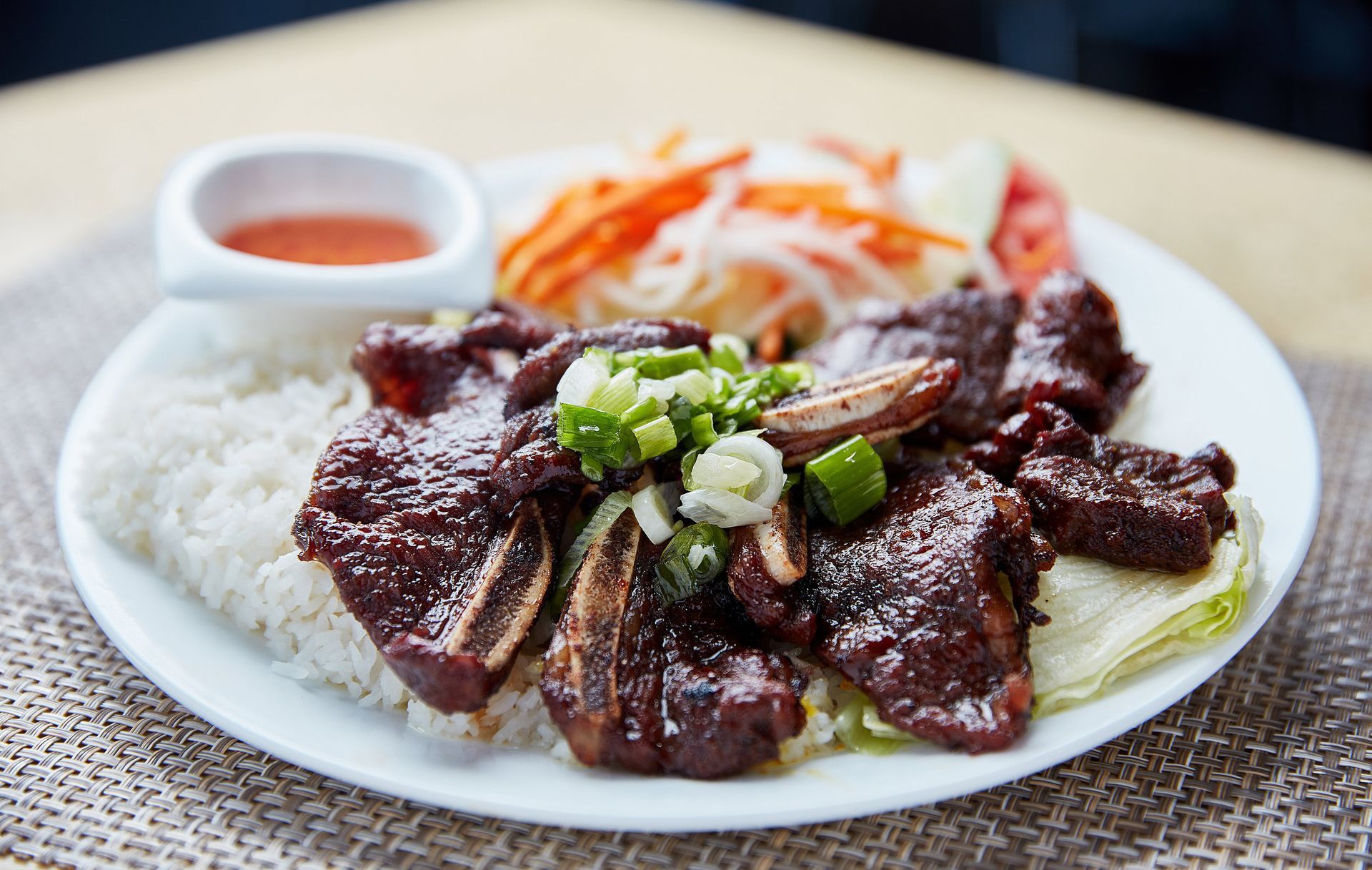 A white plate topped with meat and rice on a table.