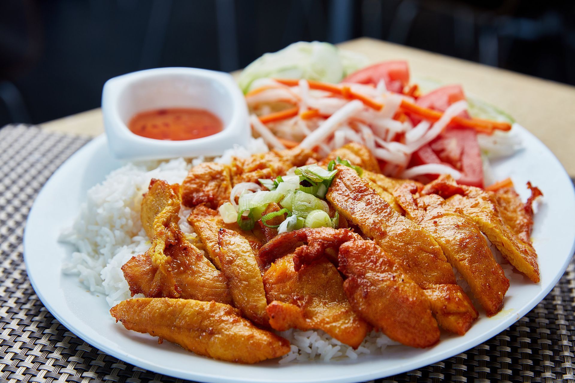 A plate of food with rice , meat and vegetables on a table.