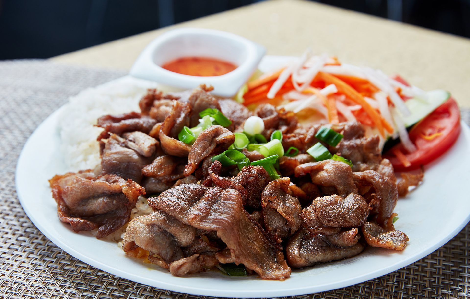 A white plate topped with meat and vegetables on a table.