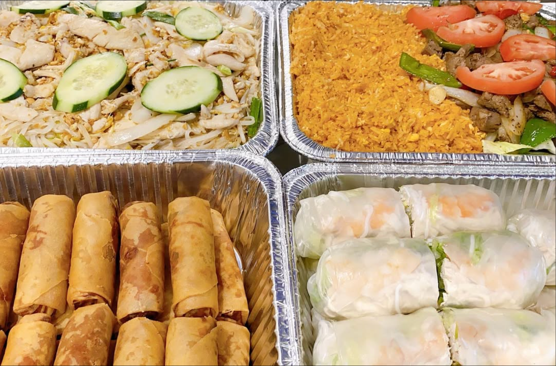 There are many different types of Vietnamese food in aluminum trays for a catered event