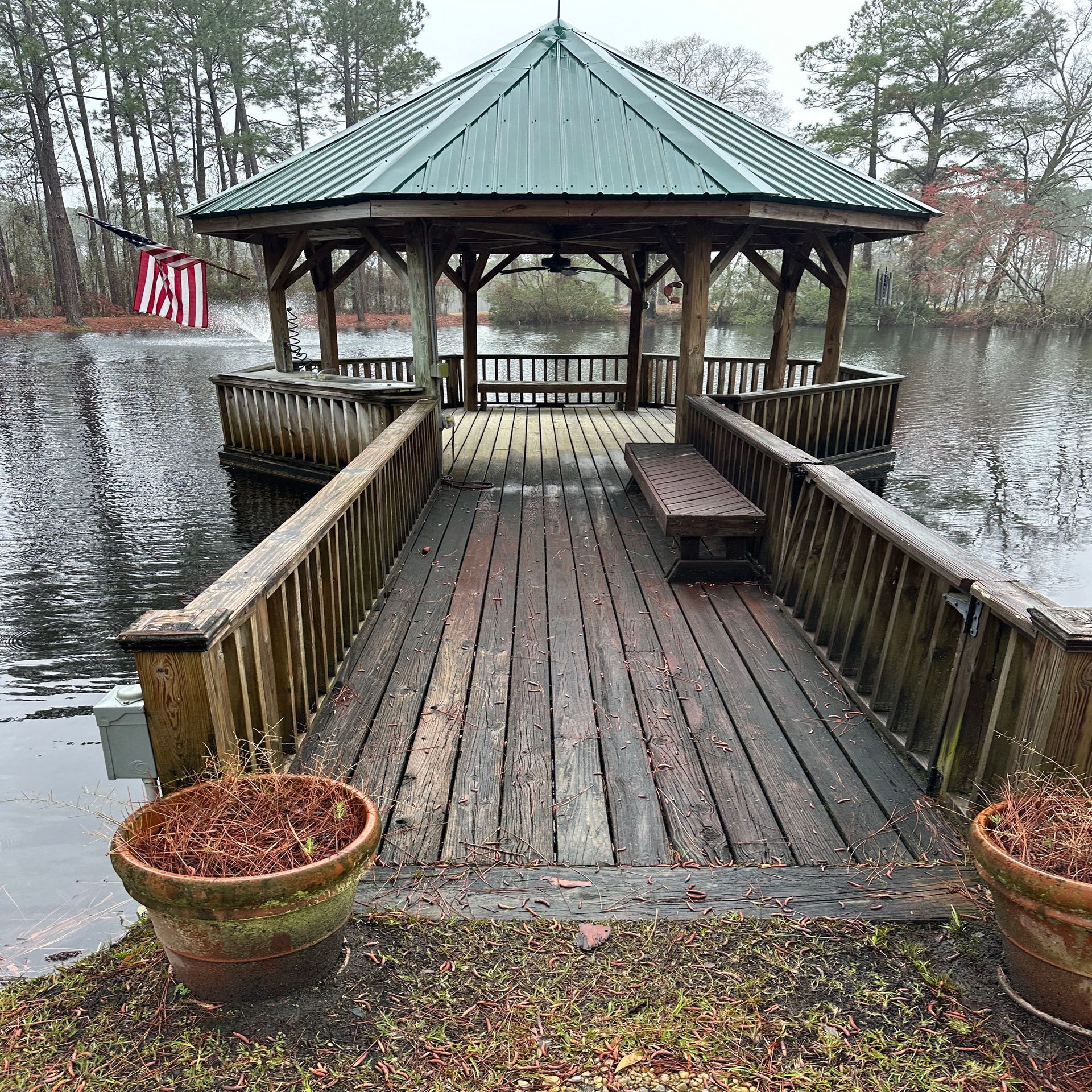 A gazebo is sitting on top of a wooden deck overlooking a lake.