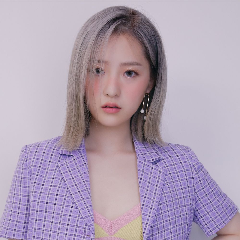 Portrait of a woman in a lavender blazer and pastel top against a plain background