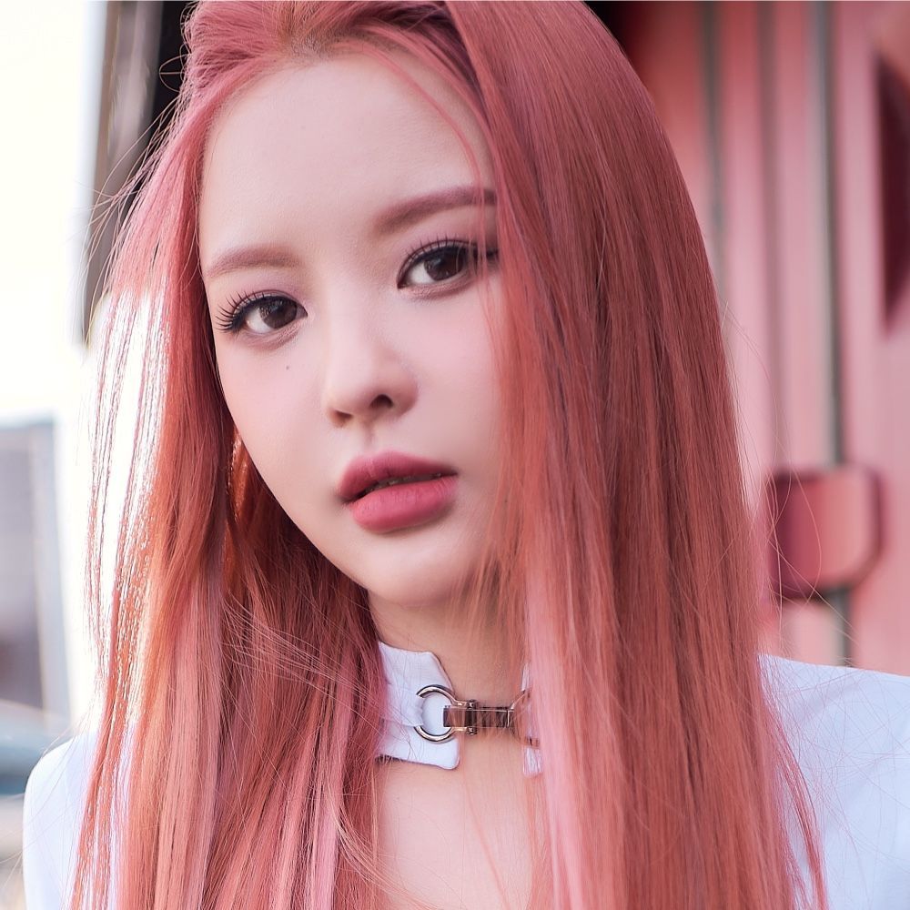 Portrait of a person with long pink hair and a white choker, looking at the camera outdoors
