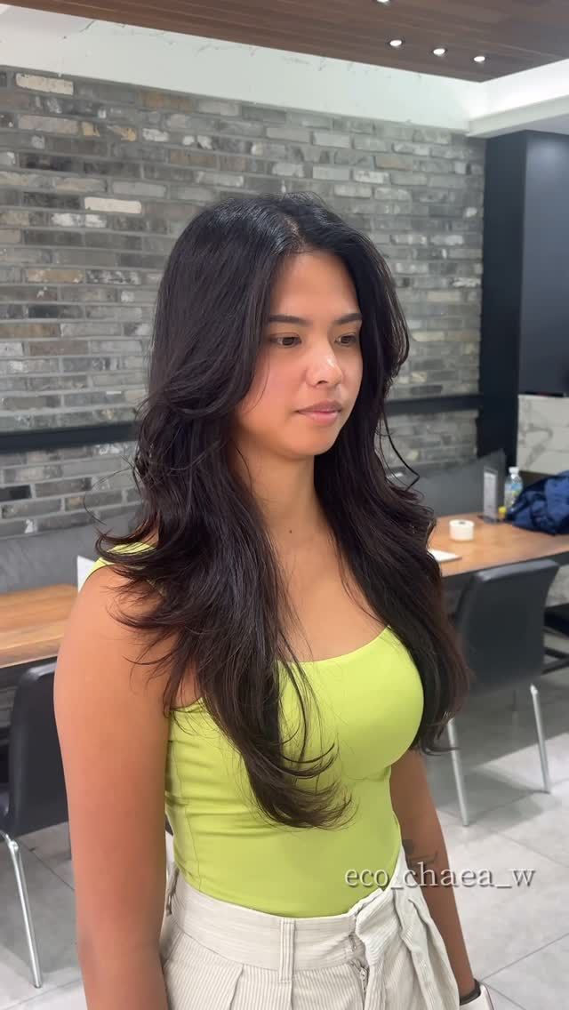 Young woman in a neon green top standing indoors near a gray stone wall