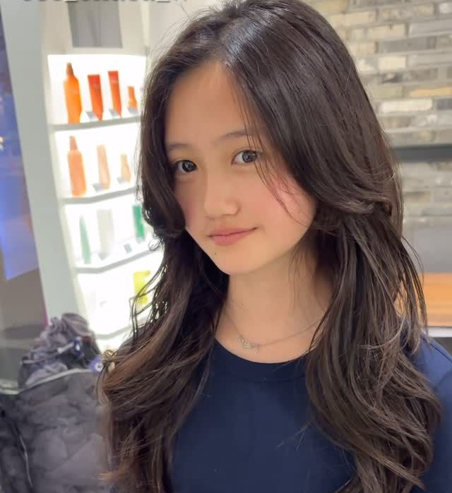 Portrait of a person with long dark hair in a navy top, standing in a bright indoor store.