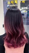 Back view of long wavy black-to-magenta hair in a salon setting