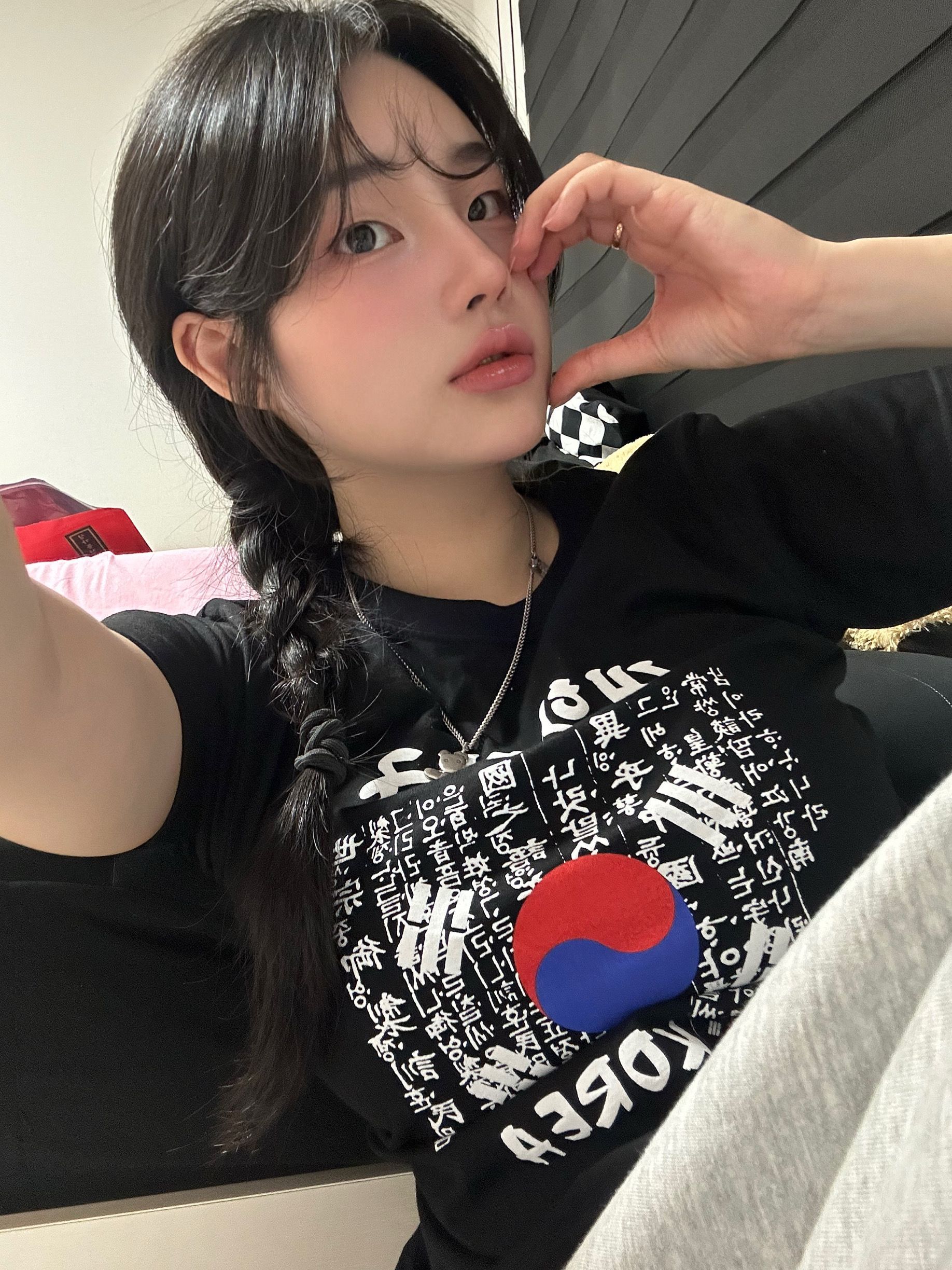 Person taking a selfie indoors, wearing a black shirt with a red and blue graphic.