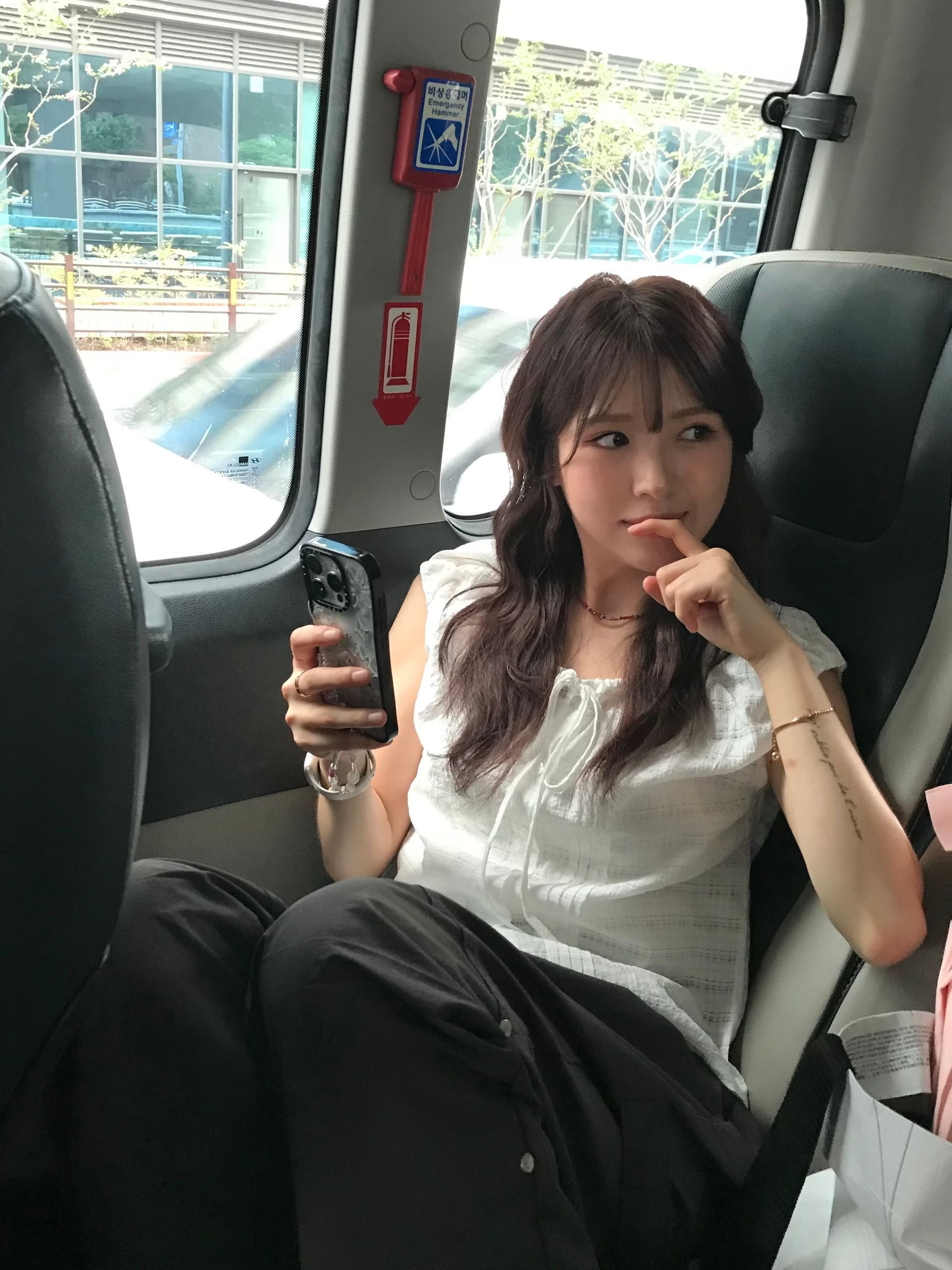 Passenger seated on a train, holding a phone and looking out the window with a thoughtful expression.