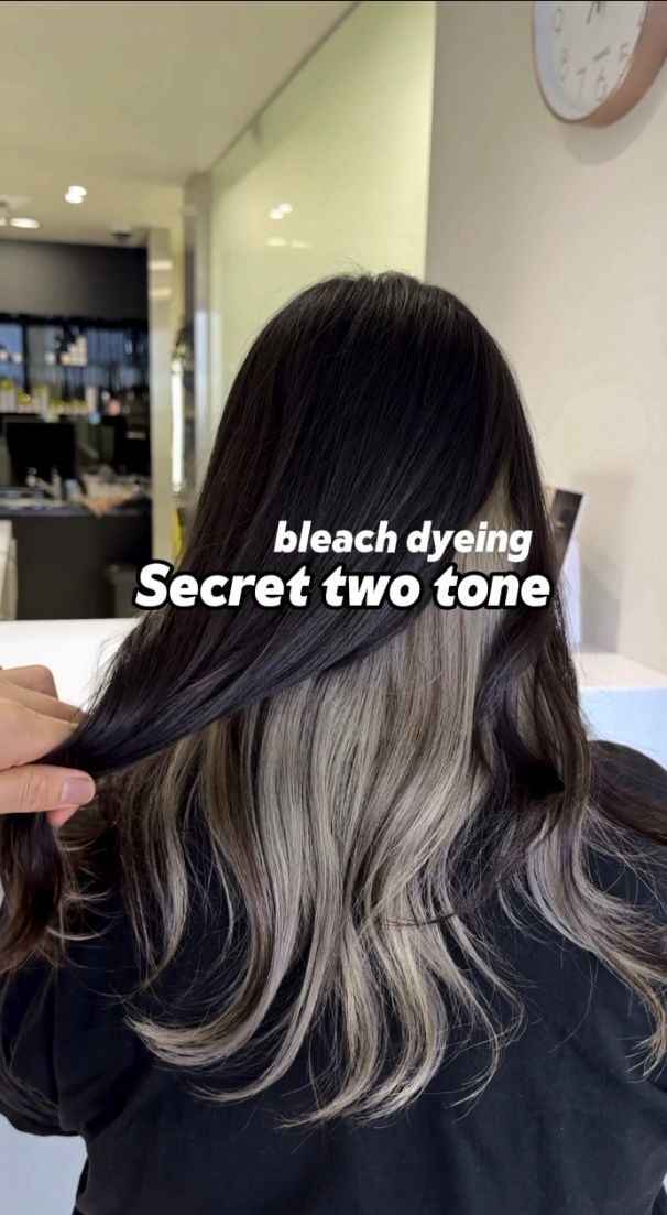 Back view of long dark hair with blonde bleached secret two-tone dye in a salon chair