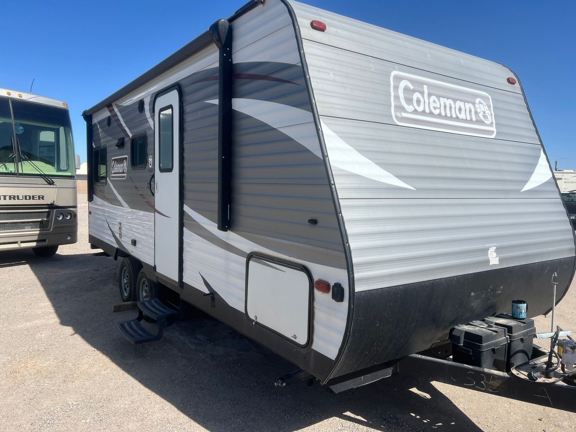 A white and black rv is parked in a parking lot.