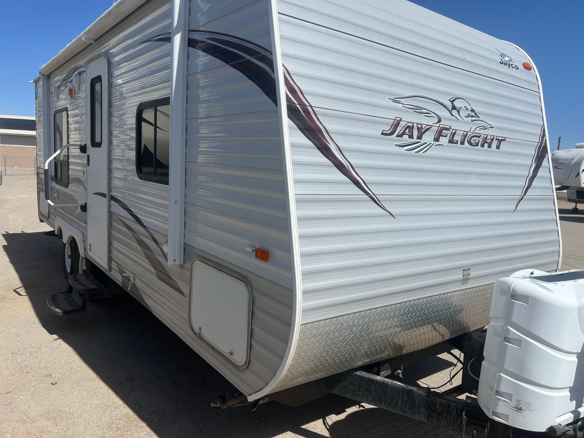 A white and black rv is parked in a parking lot.