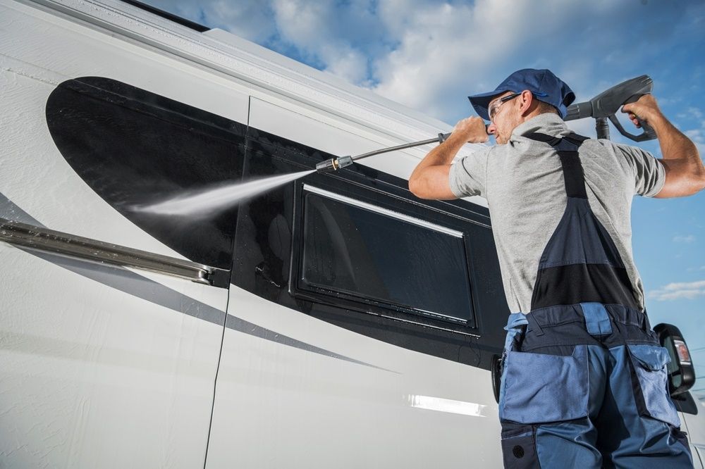 A Man Is Cleaning A Camper Van With A High Pressure Washer