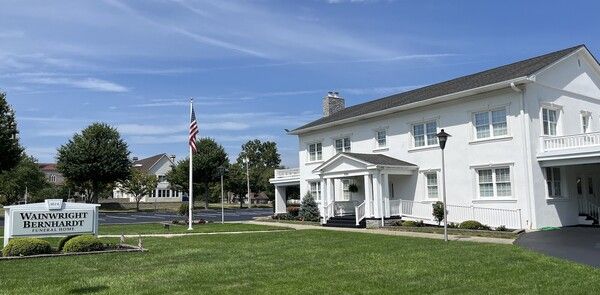 The front door of a house with a porch and plants in front of it.