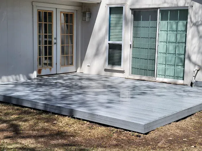 A gray deck outside a home with French doors and a sliding glass door.
