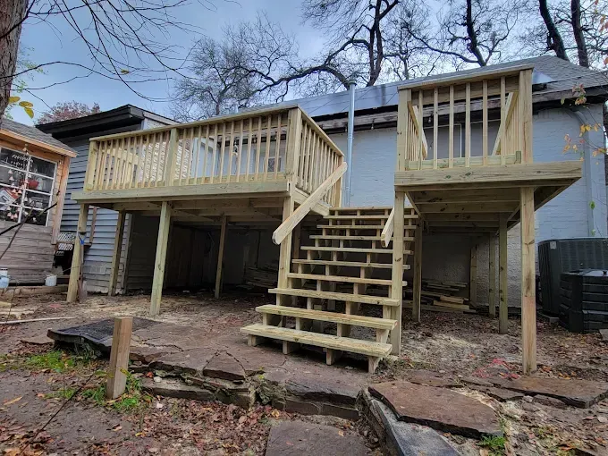 Newly constructed wooden deck with stairs, attached to a gray house.