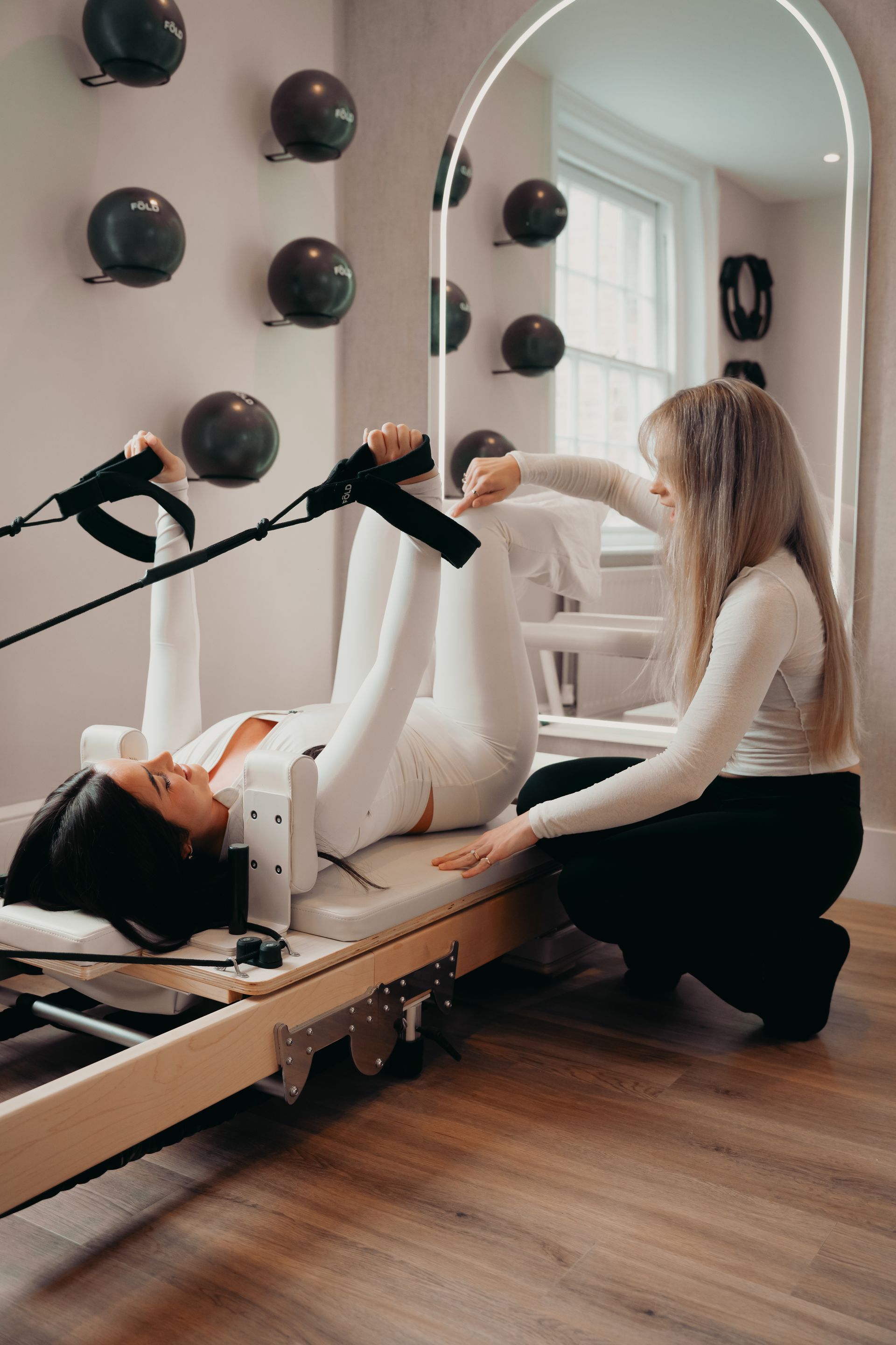 Person with tattooed arms in a meditative pose, hands clasped. Wearing neutral clothing and jewelry, outdoors.