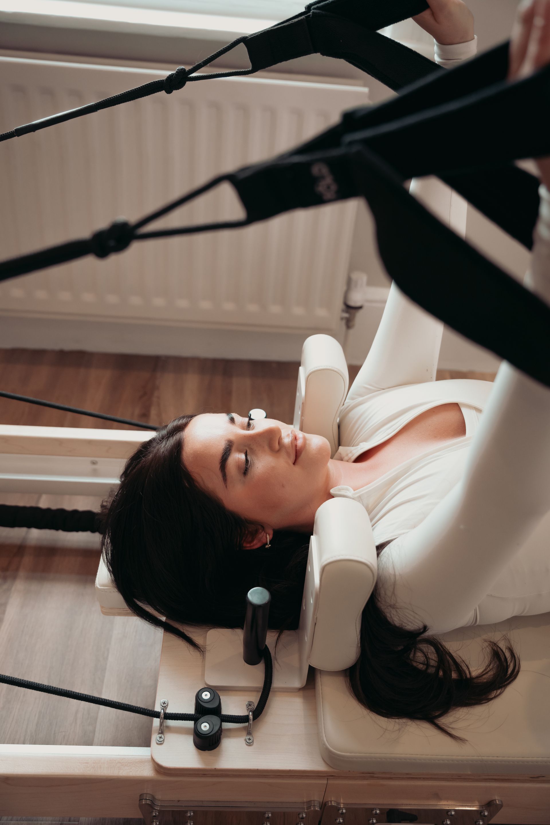 Woman in activewear stretches on a yoga mat outdoors, one leg extended.