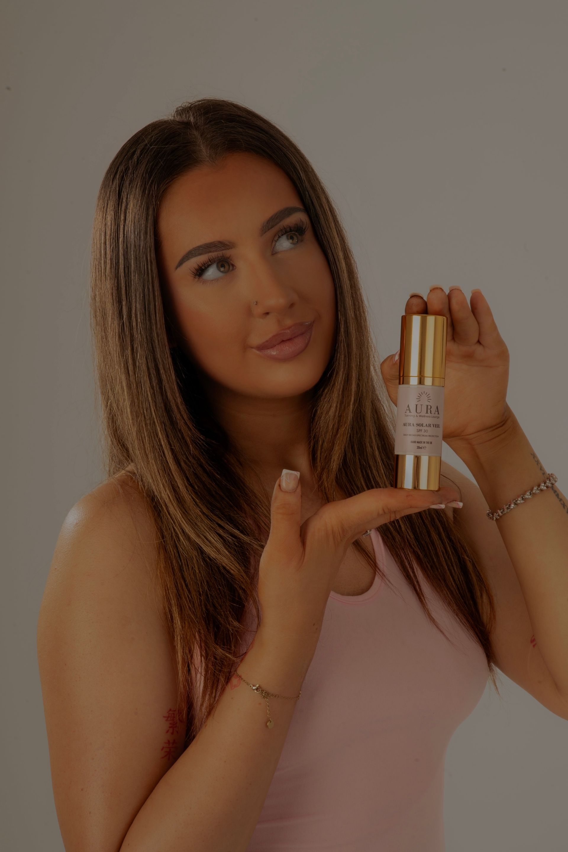 Close-up of a person's face with glowing skin, pink lips, and a hand touching their cheek.