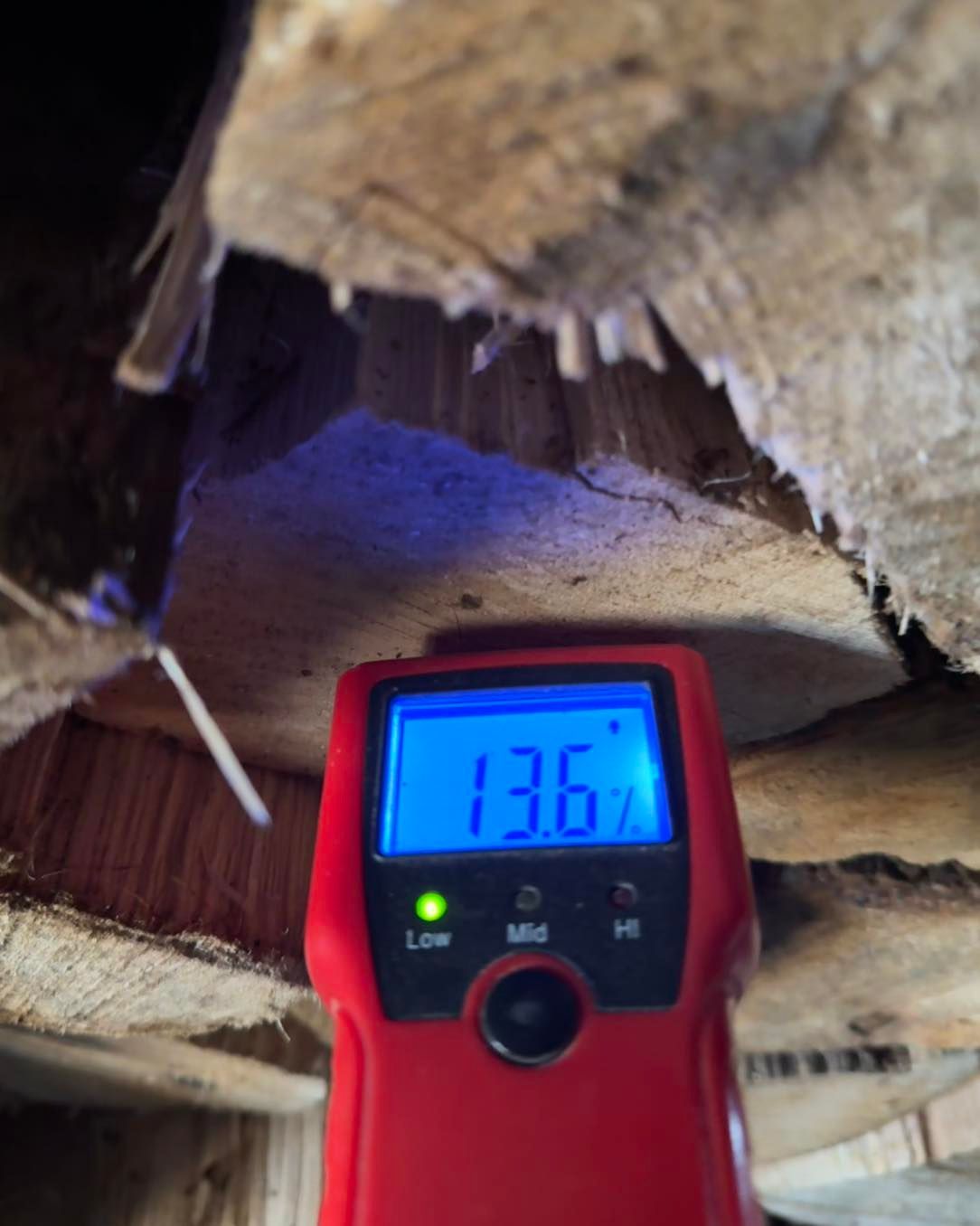 A red digital thermometer is sitting under a wooden ceiling.