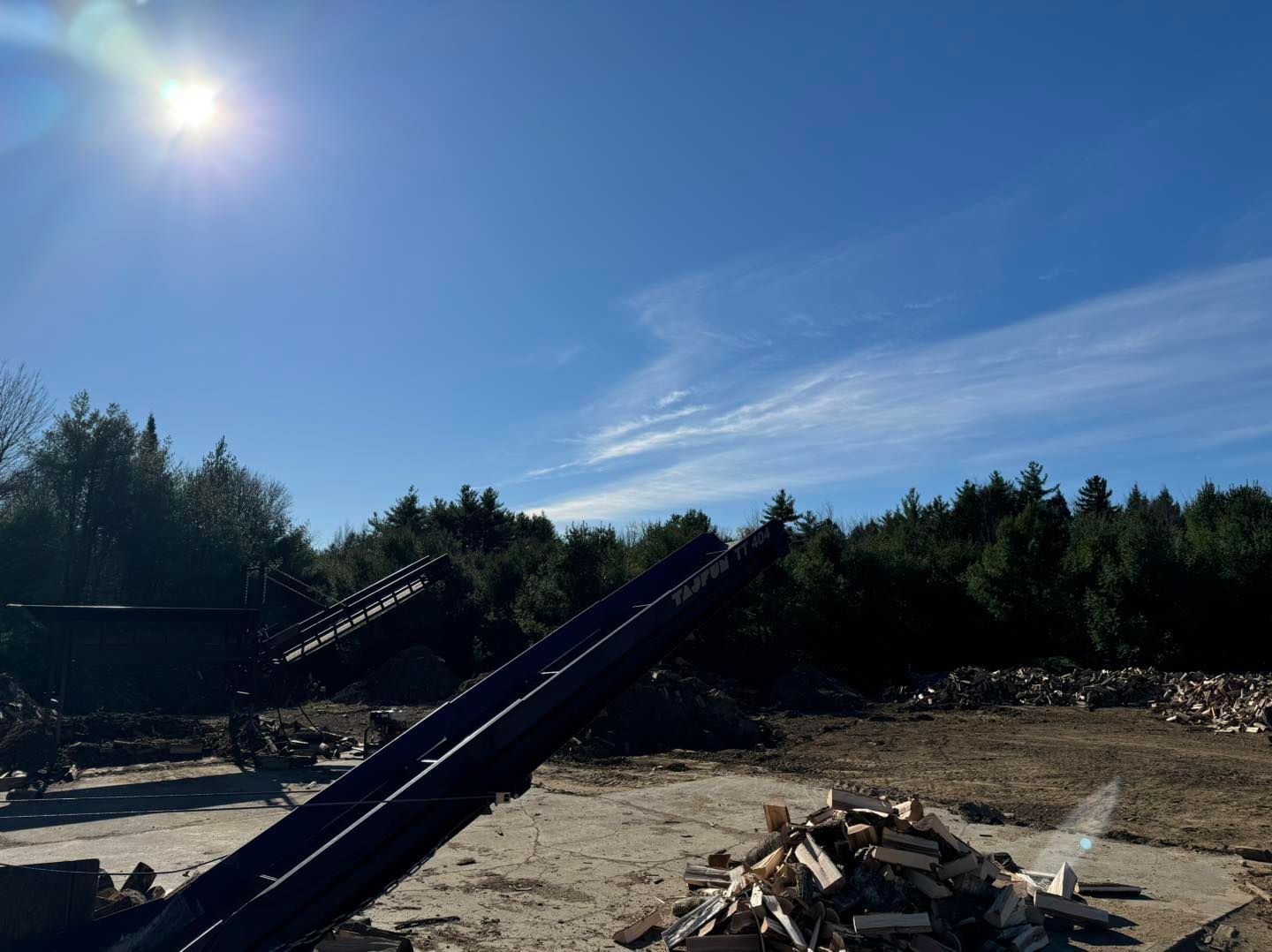 The sun is shining brightly in the sky above a pile of wood