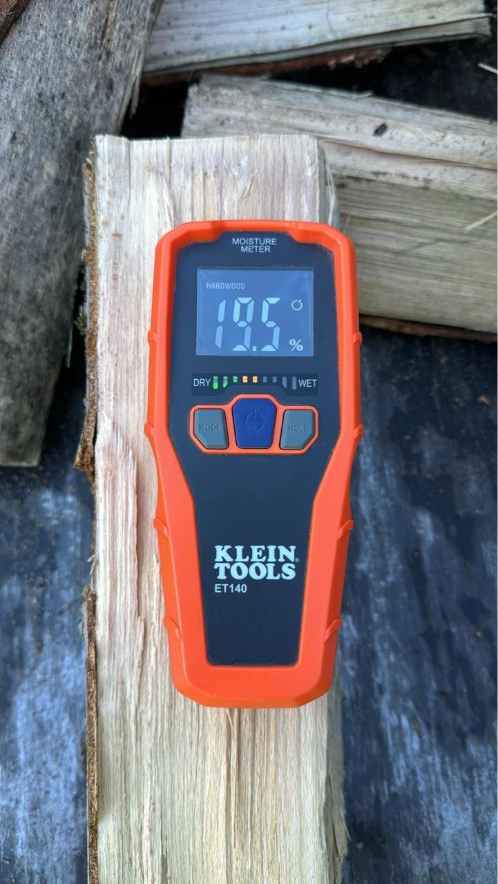 A klein tools thermometer is sitting on a piece of wood