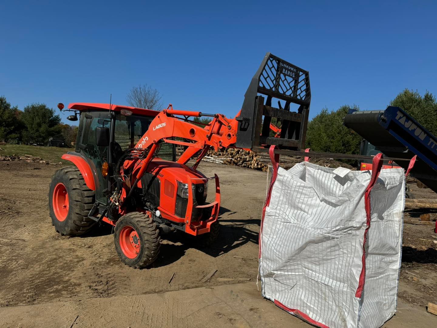 A large bag is being lifted by a tractor.