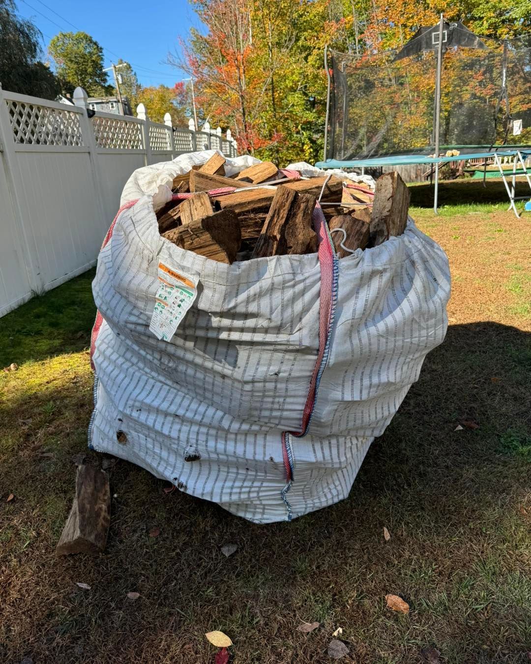 A bag of wood is sitting on the ground in a yard.