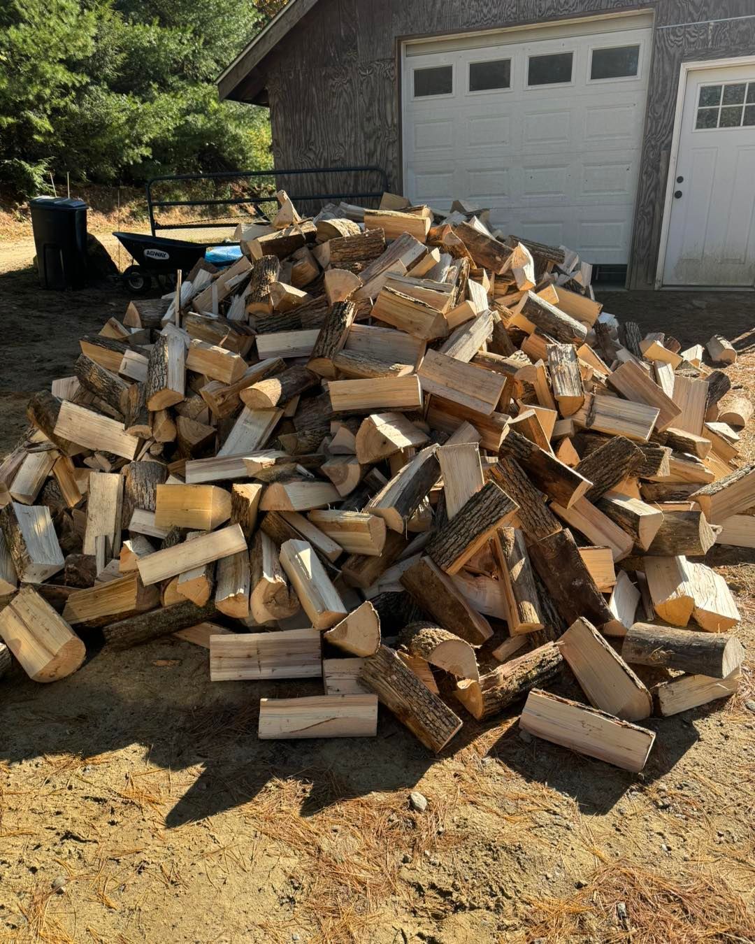 A pile of wood is sitting in front of a garage door.
