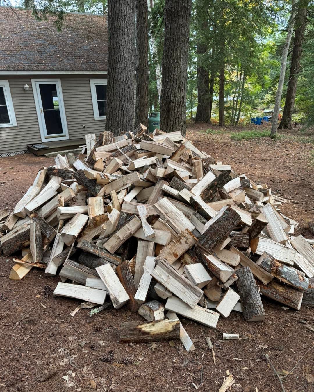 A pile of wood is sitting in front of a house.