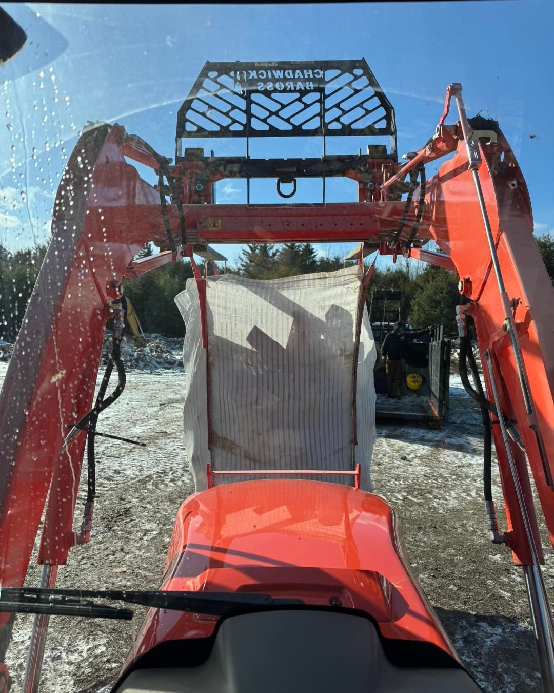 A large orange tractor is parked in the snow