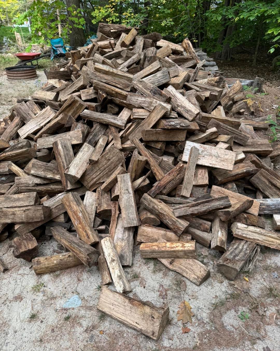 A pile of wood is sitting on the ground in a yard.